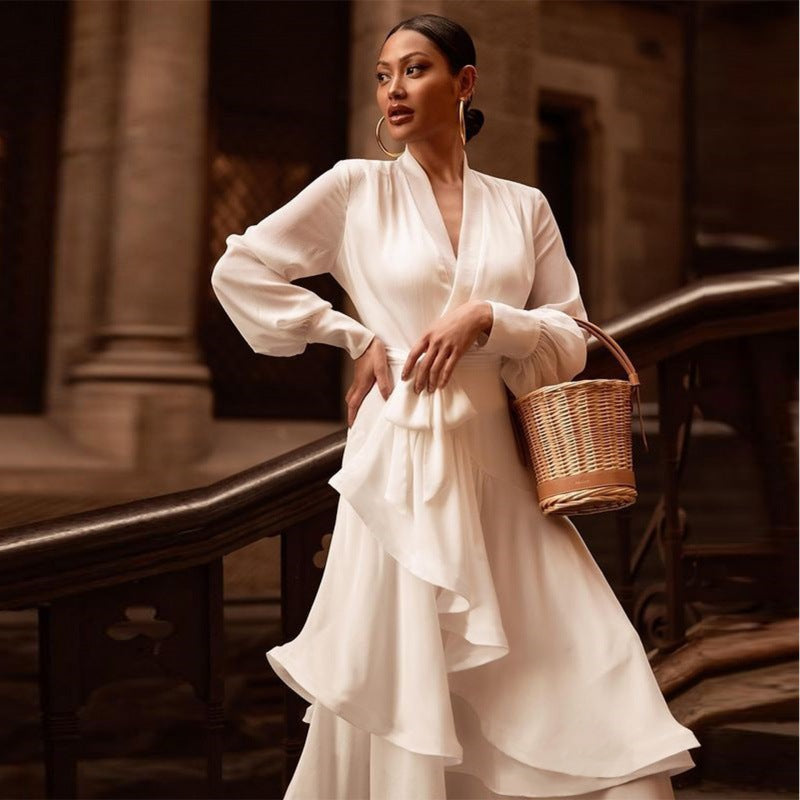 V-neck white prom dress with flowing design and feminine silhouette, styled with heels and a woven handbag.